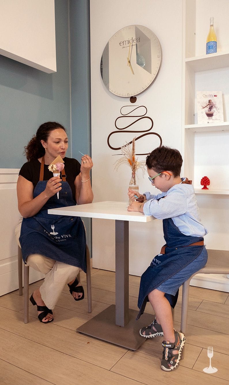 Sweets tasting room table Puglia Guests at a small table tasting a cone and a cup of gelato in the tasting room.