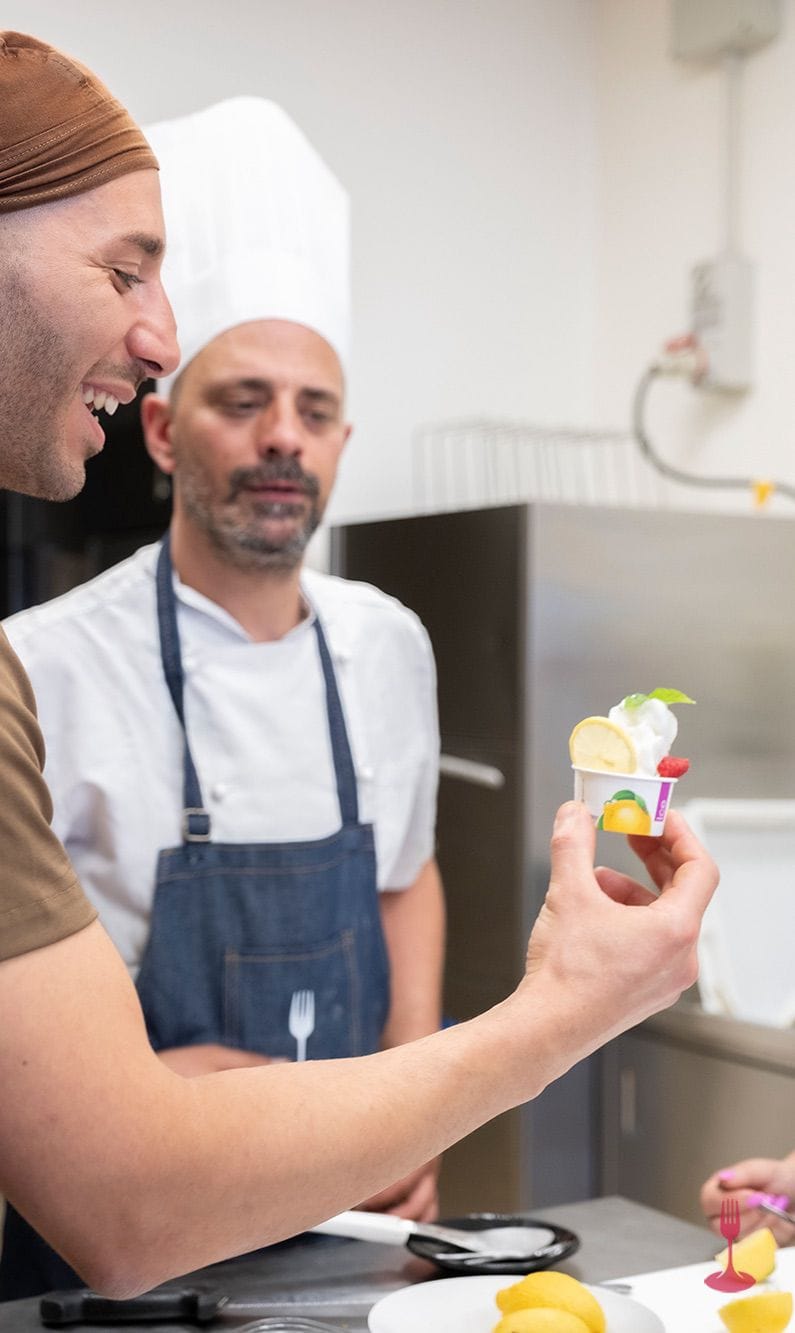 Gelato tasting cup lemon mint Pastry chef holding up a gelato cup topped with lemon, mint and raspberry.