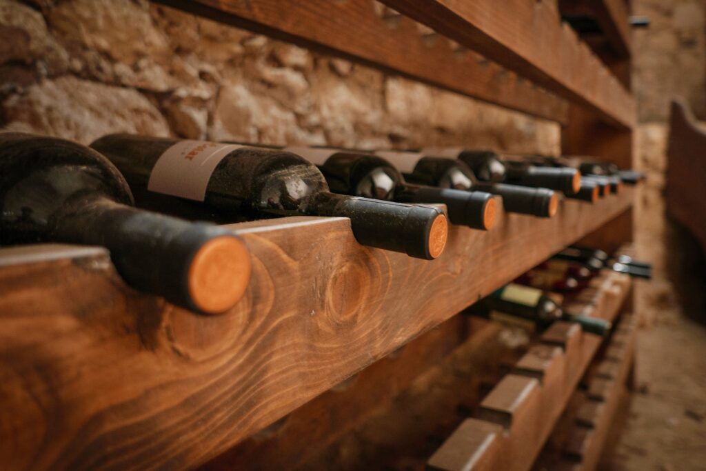 Serie di bottiglie di vino custodite su scaffali di legno in una cantina pugliese.