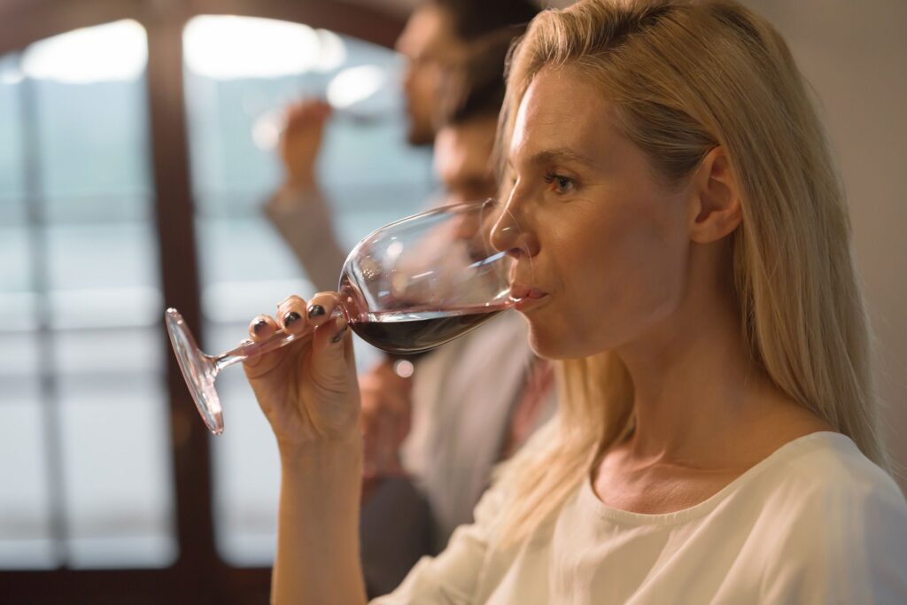 Giovane donna assaggia un calice di vino rosso.