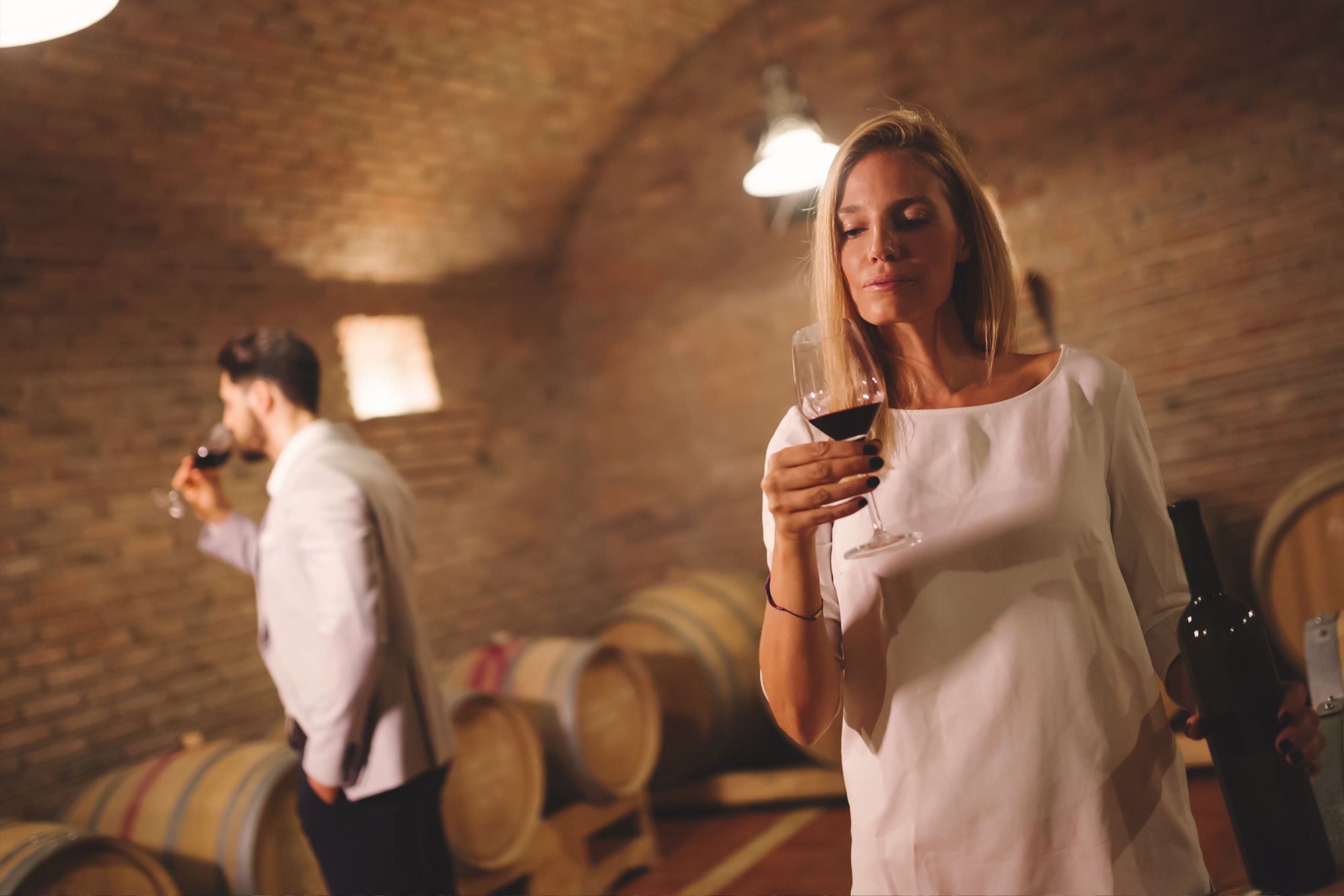 Two people tasting wines inside a Apulian cellar.