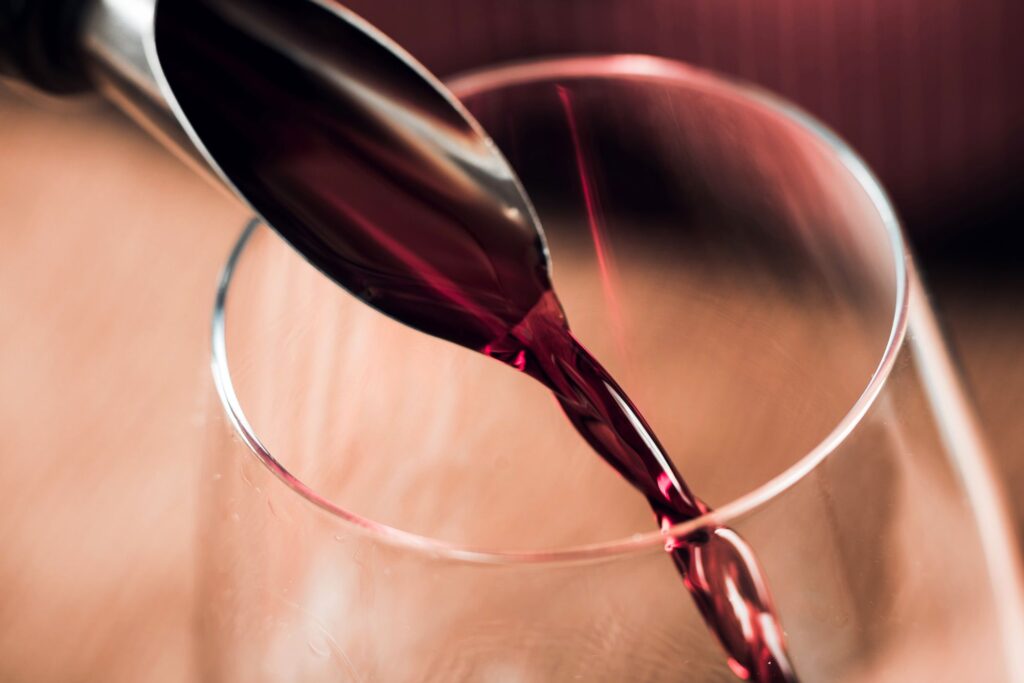 Primissimo piano di vino rosso versato all’interno di un calice.